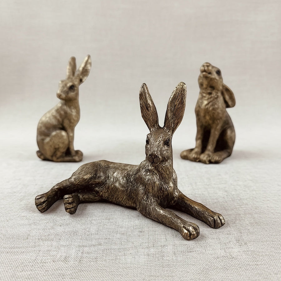 Three bronze rabbit figurines on a textured surface