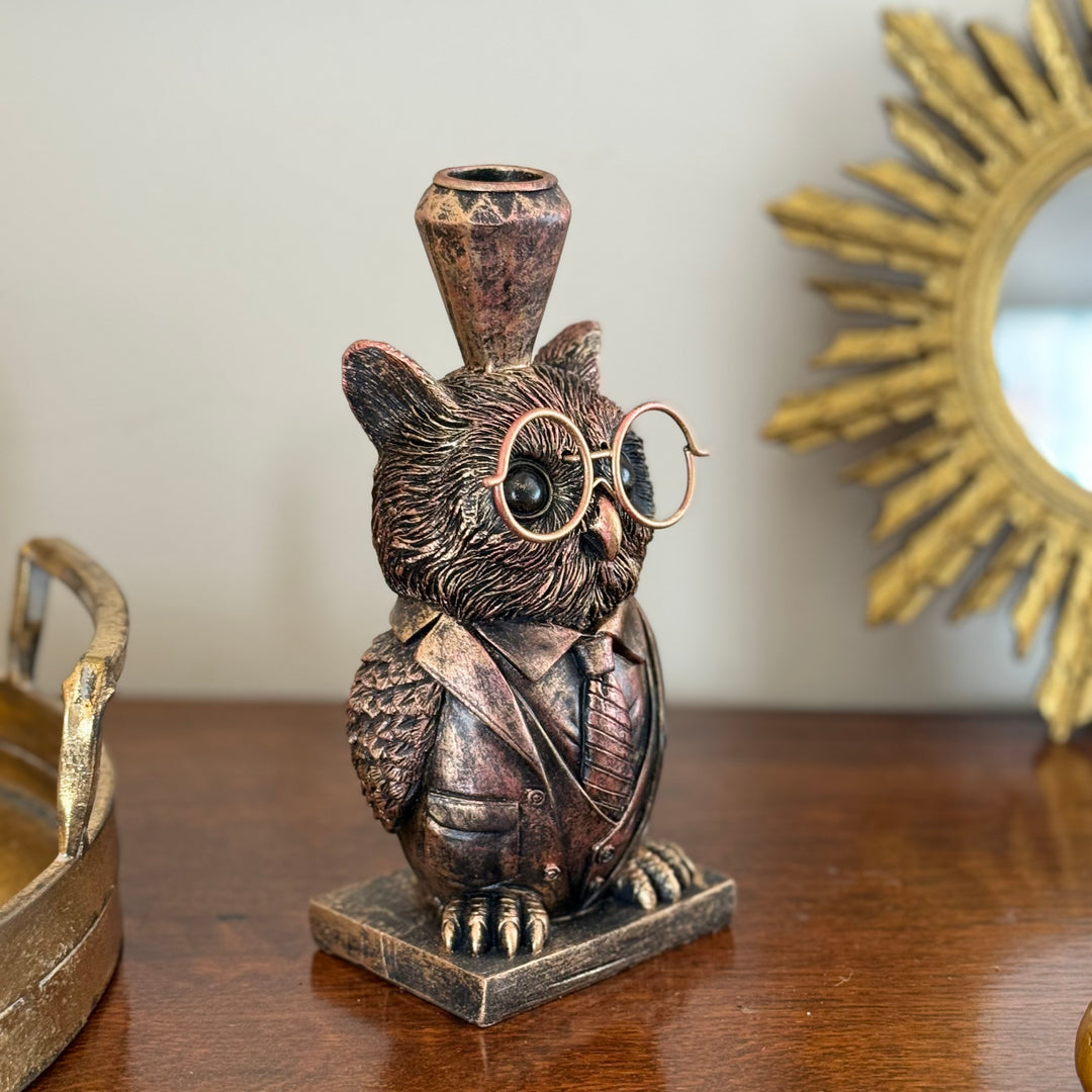 Bronze owl figurine with glasses and a top hat on a wooden surface