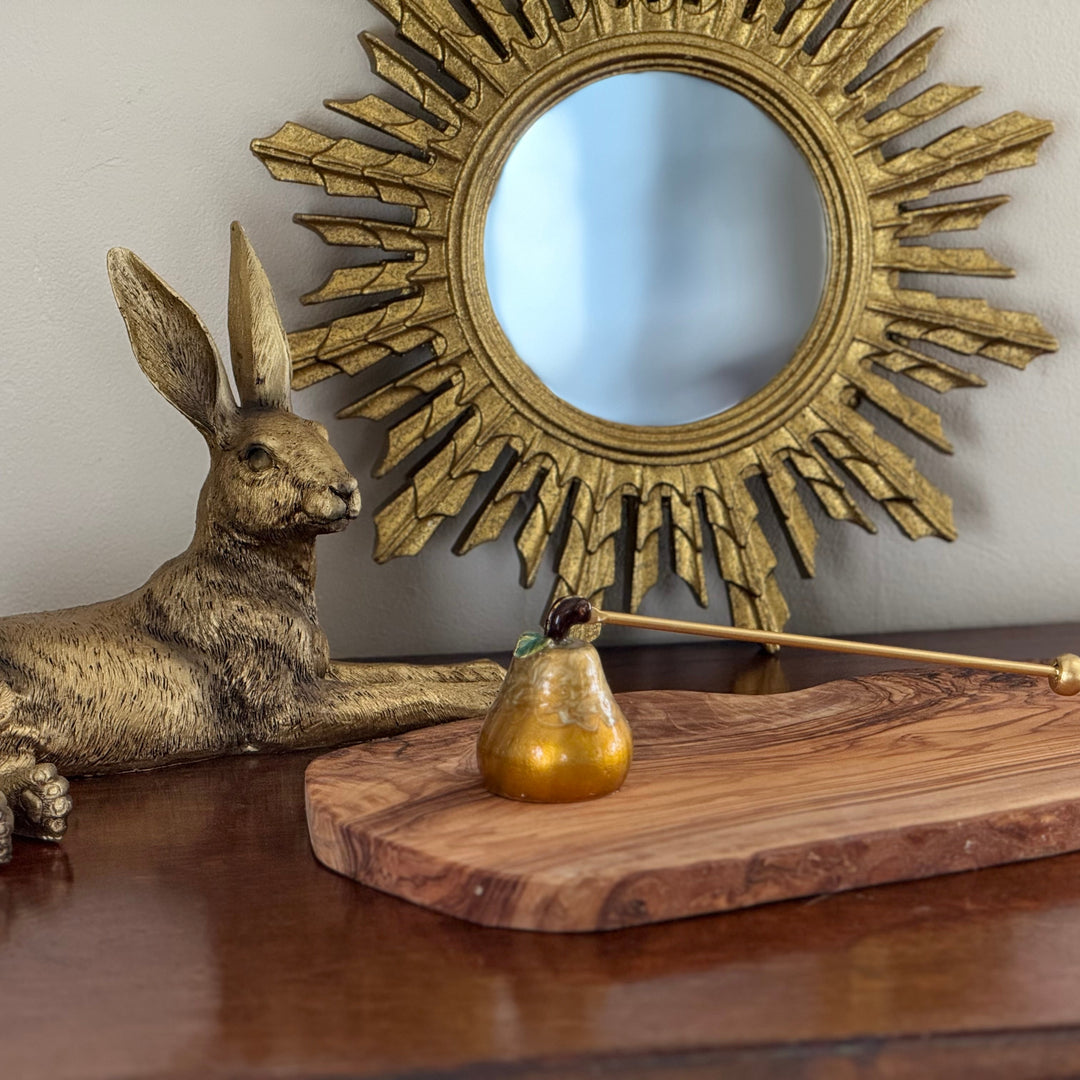 Decorative setup with a sun-shaped mirror, rabbit sculpture, and wooden items on a surface.