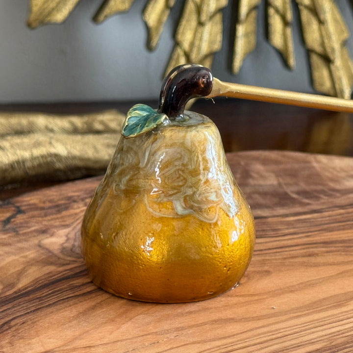 Decorative pear-shaped object with a leaf on a wooden surface