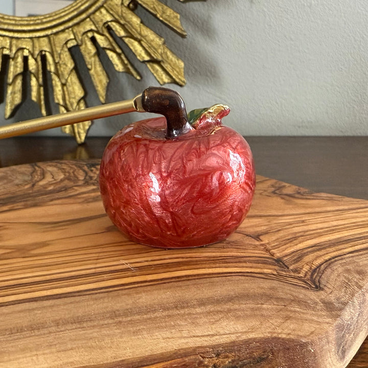 Decorative red apple with gold stem on a wooden surface