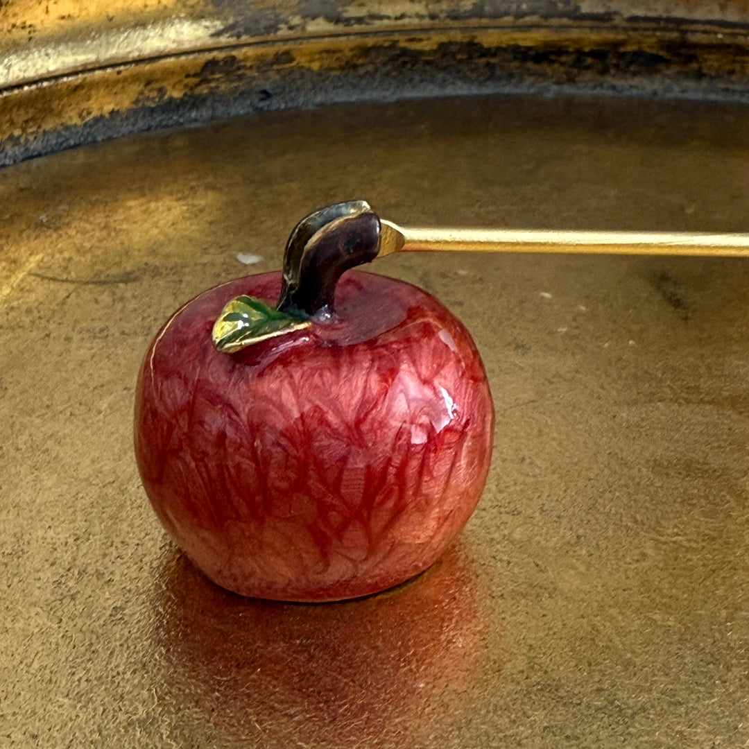 Close-up of a apple-shaped candle snuffer on a reflective surface