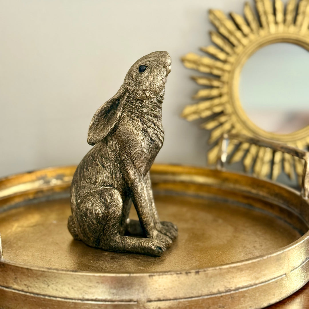 Bronze hare figurine on a gold circular tray with a sun-shaped small mirror in the background