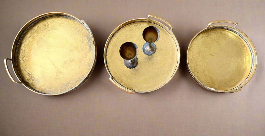 Three gold serving trays  on a wooden surface