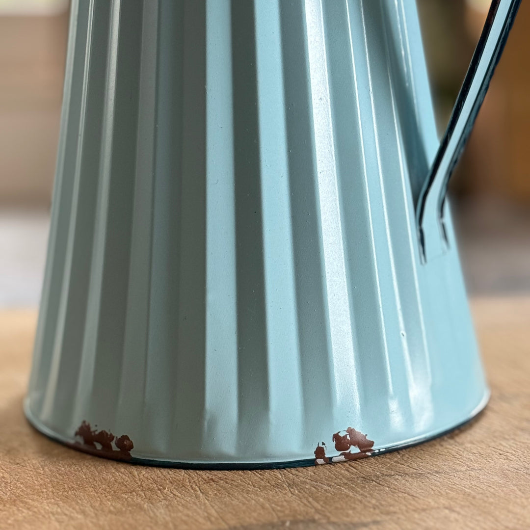 Close-up of a light blue metal jug on a wooden surface