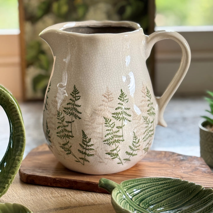 Ceramic pitcher with fern design on a wooden surface