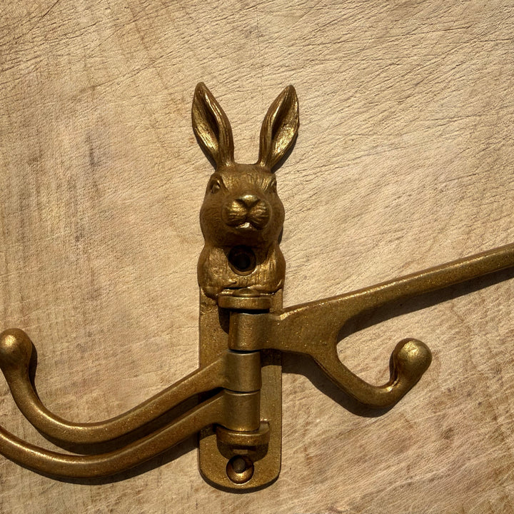 A vintage-style antique gold rabbit-shaped wall hook with two hanging hooks, shown mounted on a textured wood surface.