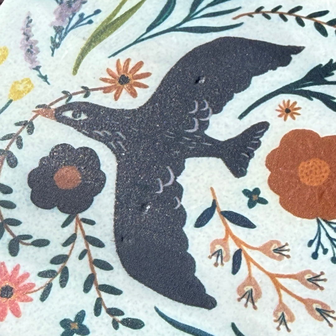 Silhouette of a bird surrounded by flowers and leaves on a patterned background