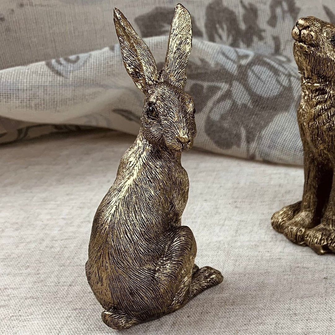 Bronze rabbit figurine on a textured surface with a blurred background
