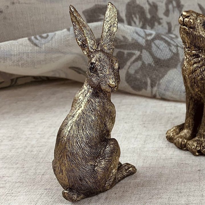 Bronze rabbit figurine on a textured surface with a blurred background