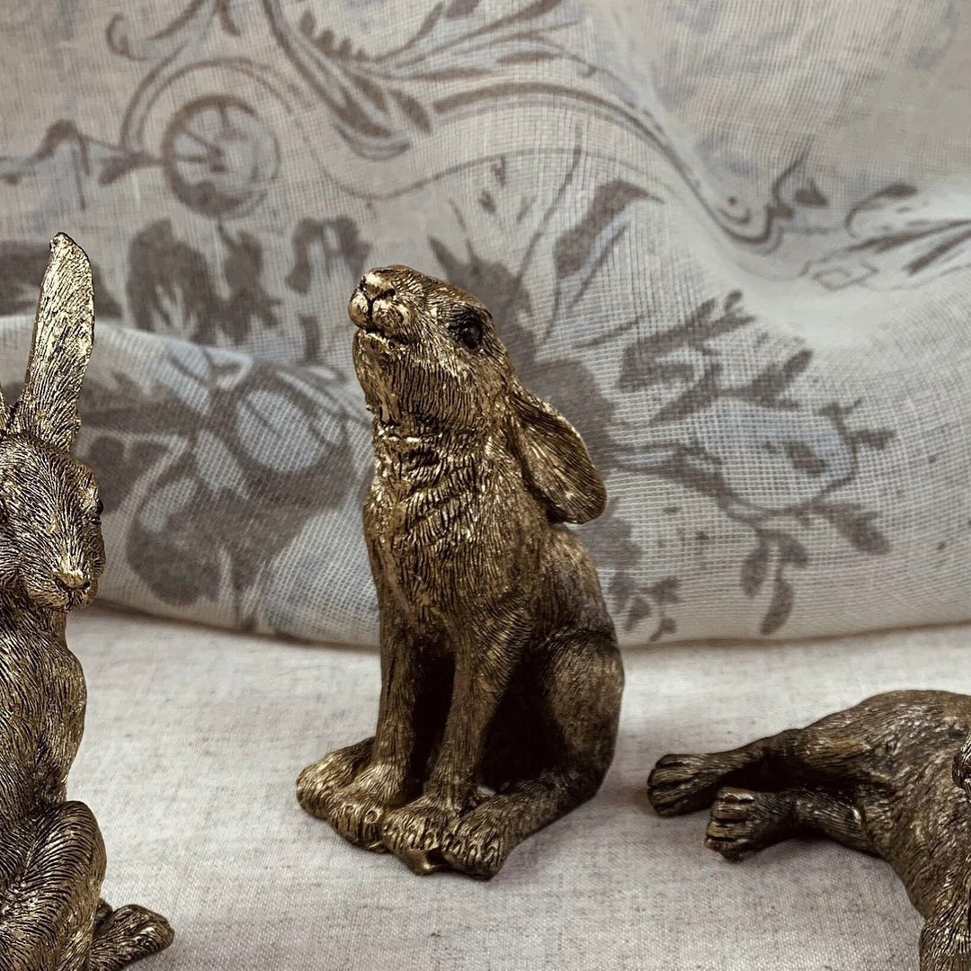 Bronze hare figurines on a textured fabric background