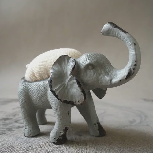 grey elephant pin cushion on a fabric surface