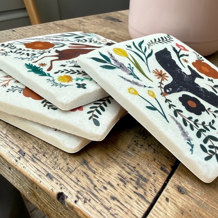 Vintage Hare Folk Art Coasters: Set of 4 resin coasters with hare and blackbird designs, botanical sprigs, and textured finish.