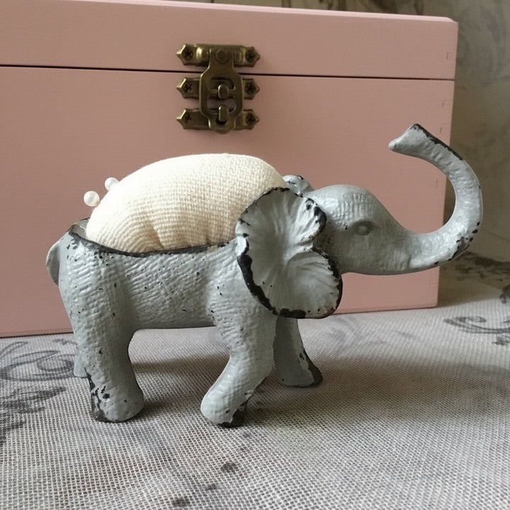 Shabby chic French grey metal elephant pin cushion with a cream hessian padded back and two pins.