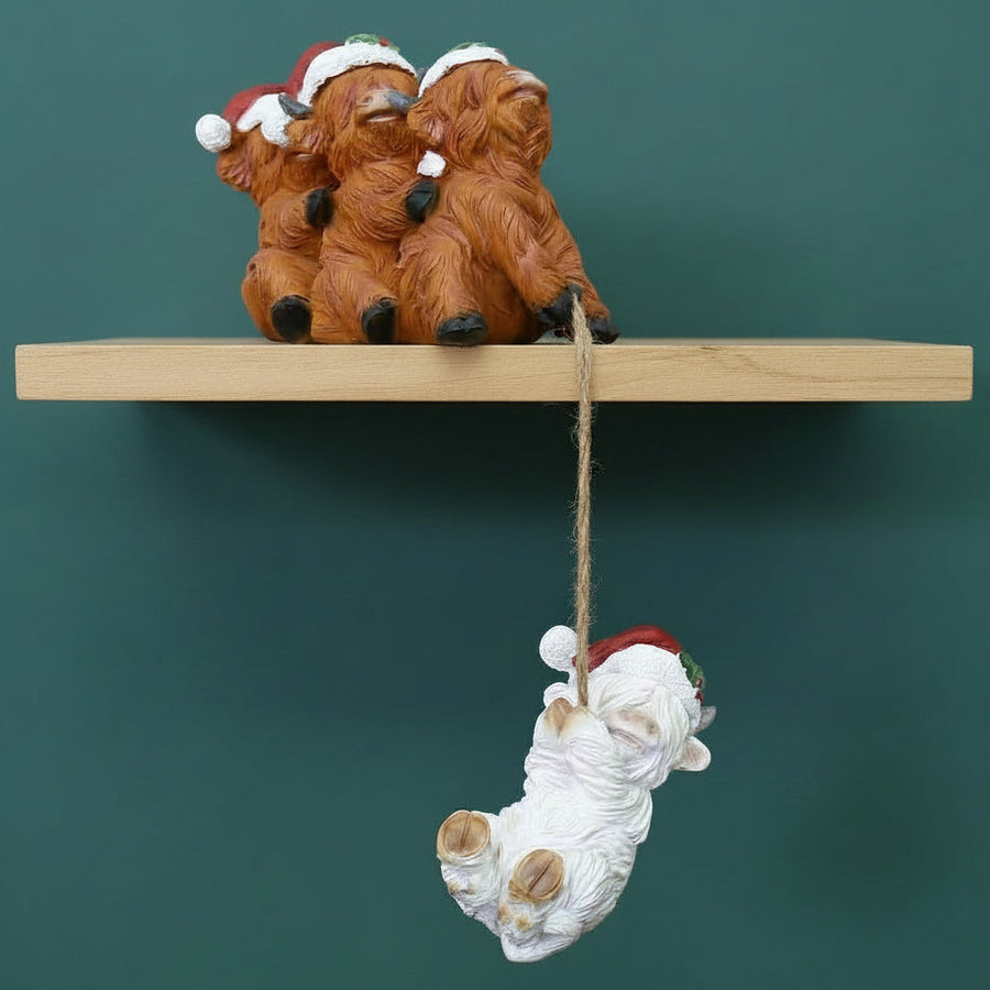 Decorative Christmas ornament - 3 brown cows with a white cow with a red Santa hat hanging from a wooden shelf.