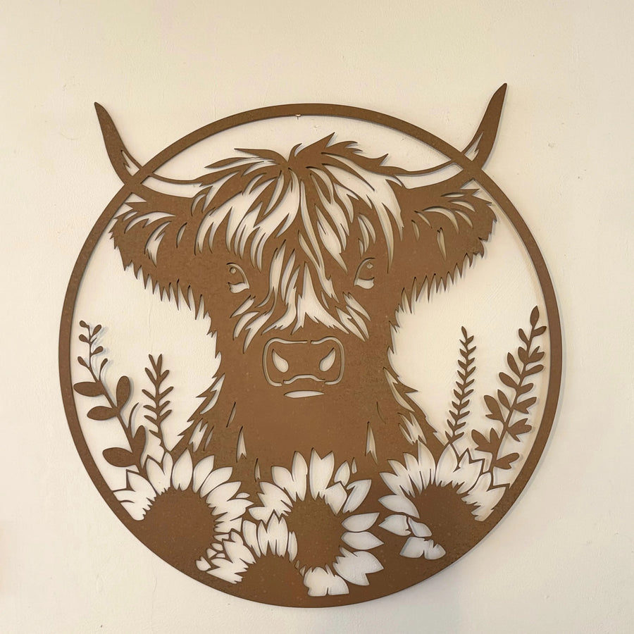Vintage Hare large circular metal wall plaque featuring a rustic rusty Highland cow surrounded by sunflowers and foliage.