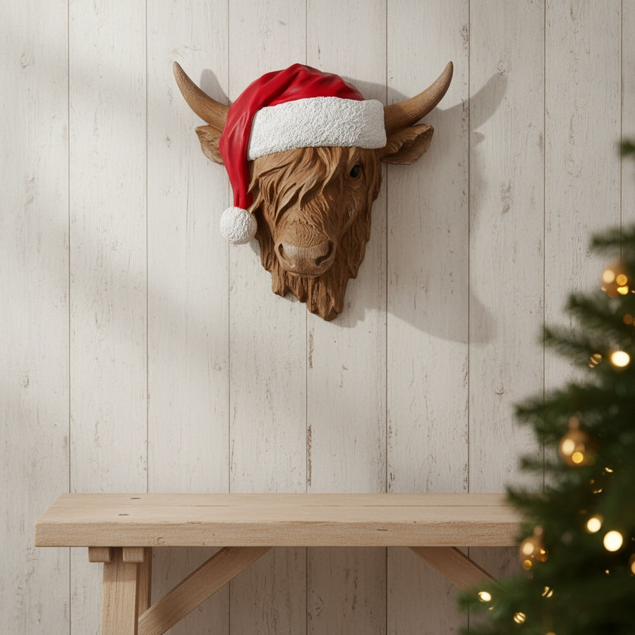 Vintage Hare resin Highland cow wall hanger wearing a festive red and white Santa hat on a rustic wood wall