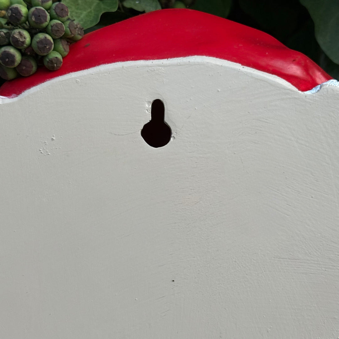 Close-up of a grey surface with a small black hole, surrounded by greenery, showing the back of the cow head
