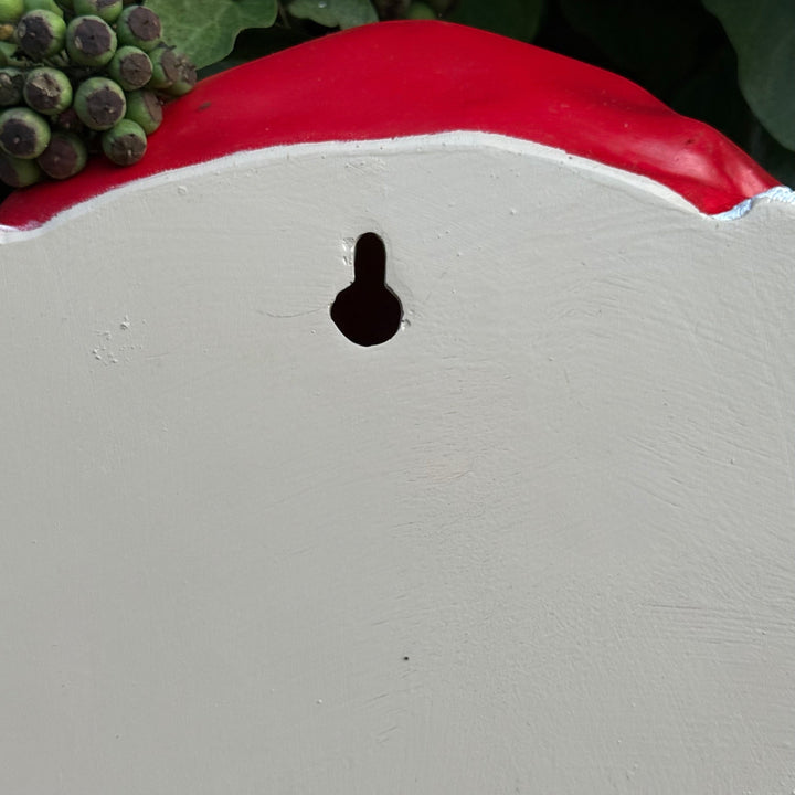 Close-up of a grey surface with a small black hole, surrounded by greenery, showing the back of the cow head
