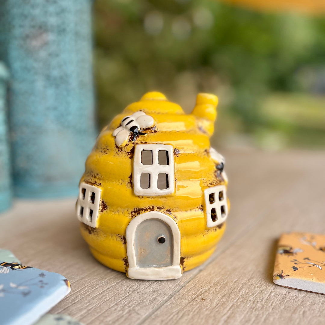 Yellow ceramic house-shaped object on a wooden surface with a blurred natural background