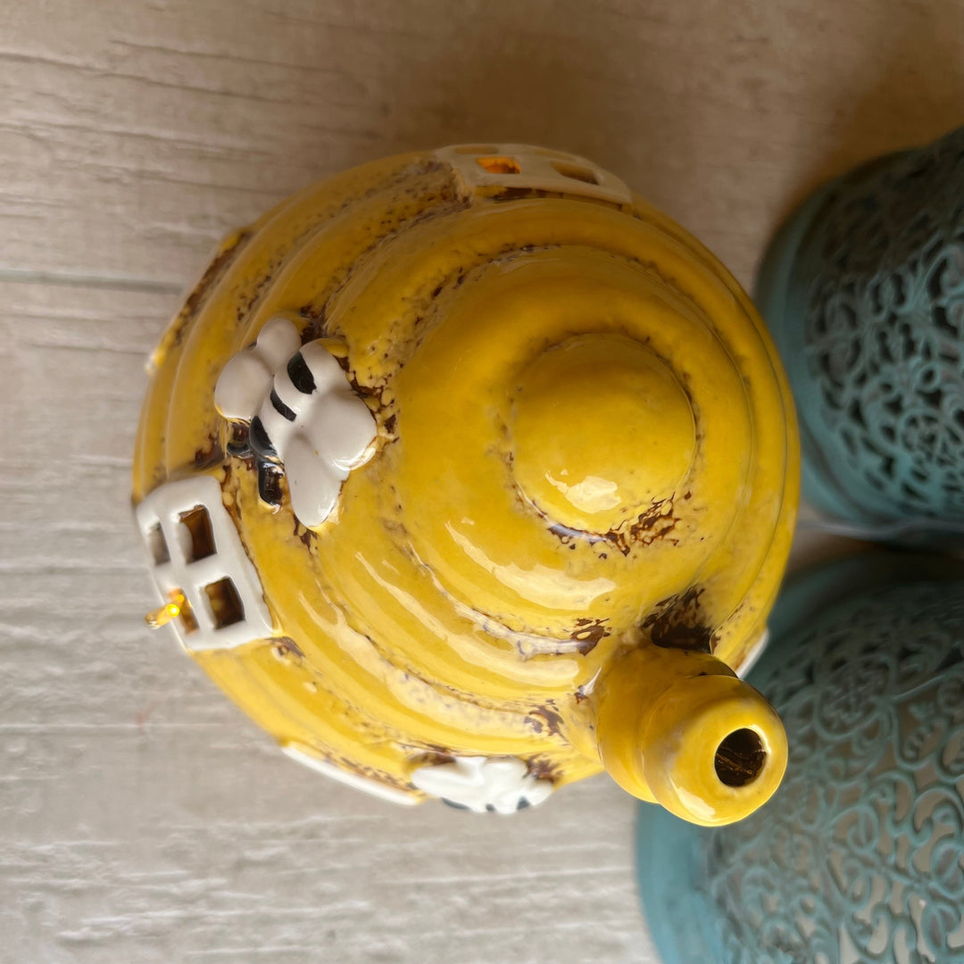 Yellow ceramic incense burner with decorative elements on a textured surface