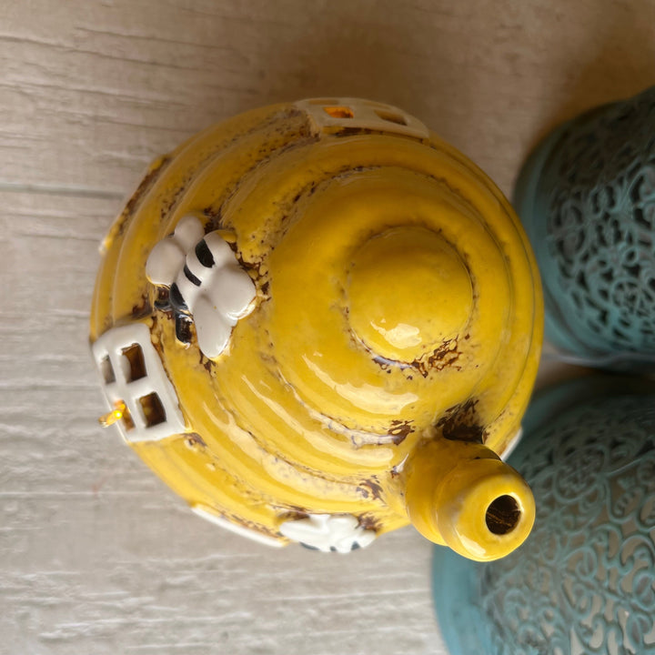 Yellow ceramic incense burner with decorative elements on a textured surface