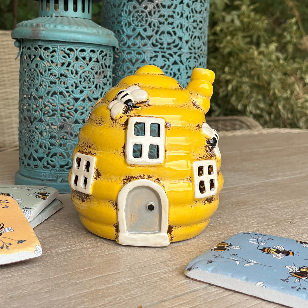 Yellow ceramic bee house with decorative elements on a wooden surface