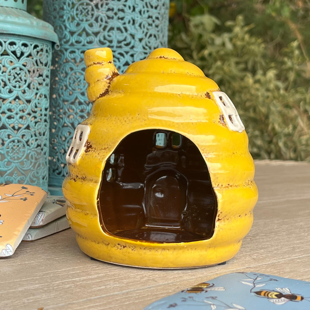 Yellow ceramic beehive-shaped object on a wooden surface with decorative elements.