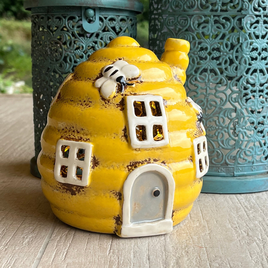 Yellow ceramic bee house with white details on a wooden surface