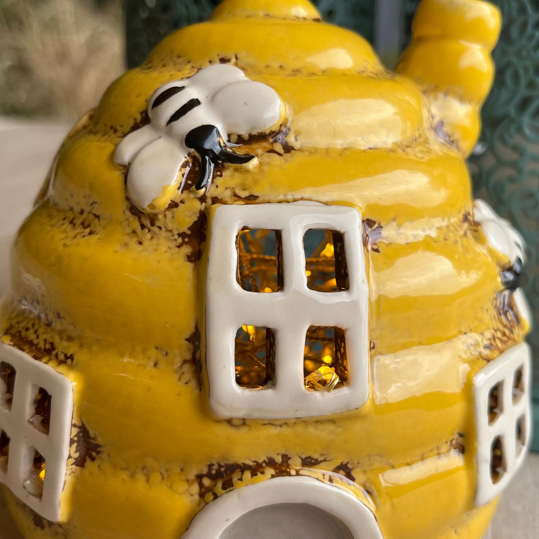Yellow ceramic beehive with a small white bee on top
